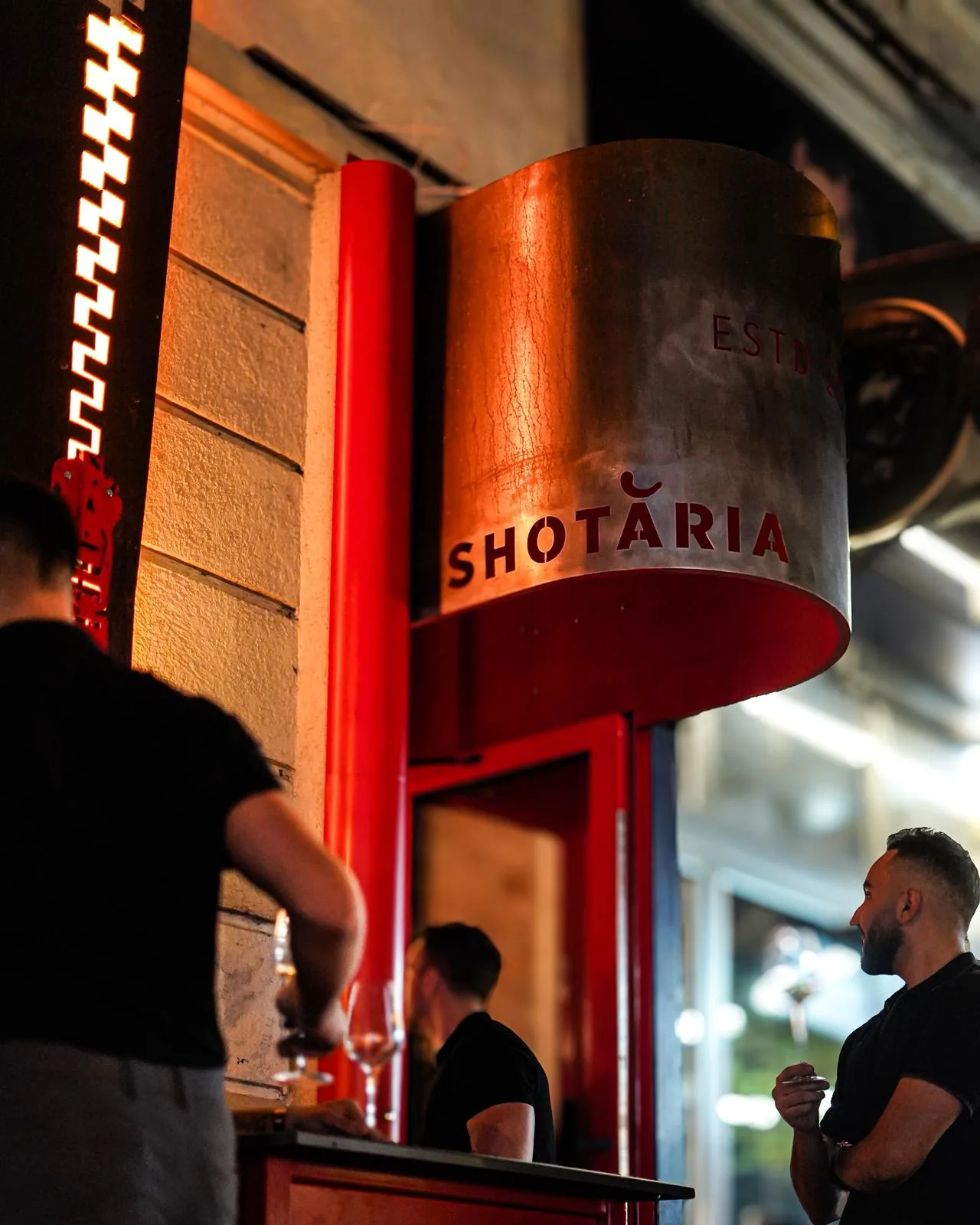 Firma Shotăria din tablă ruginită, lângă fermoarul și intrarea roșie.